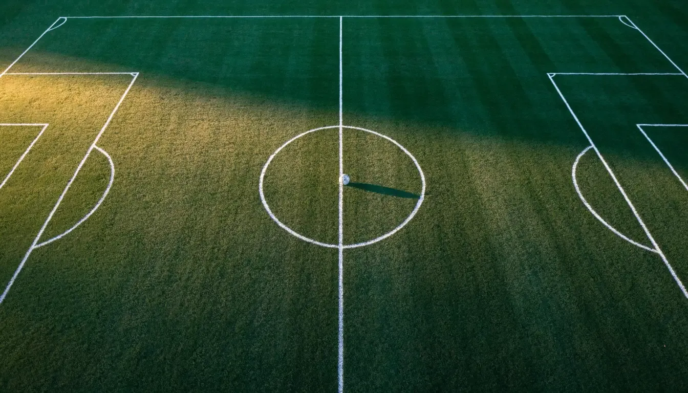 Ein Fussballplatz von oben gesehen, die Linien bilden ein helles Muster auf dem Rasen, Drohnenperspektive in der Morgendämmerung.