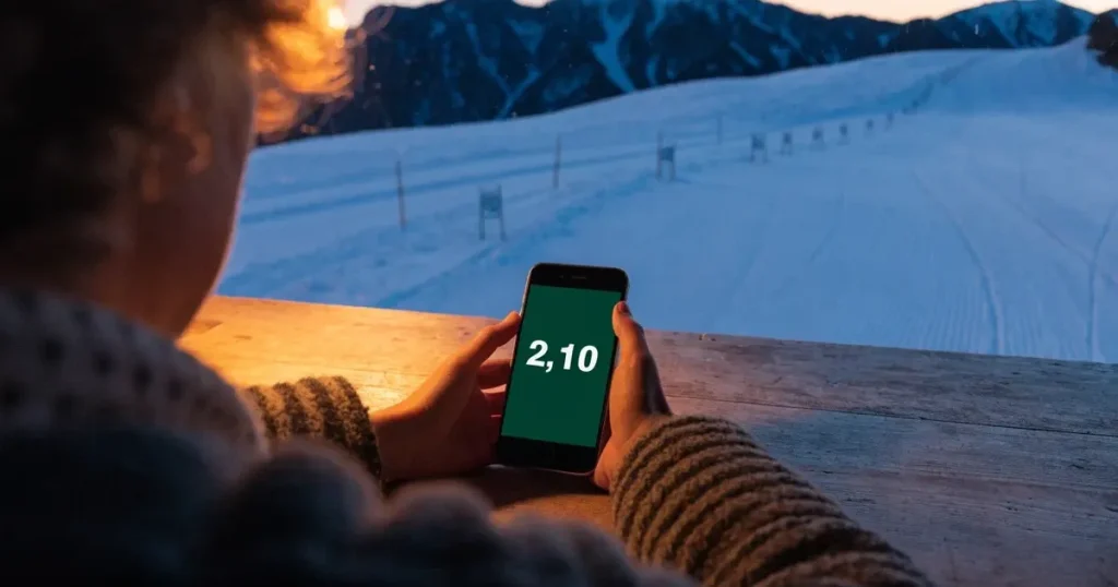 Ein frisch präparierter Hang mit Slalomstangen in einer Reihe im ersten Morgenlicht, Schneespuren im Hang und Berge im Hintergrund.